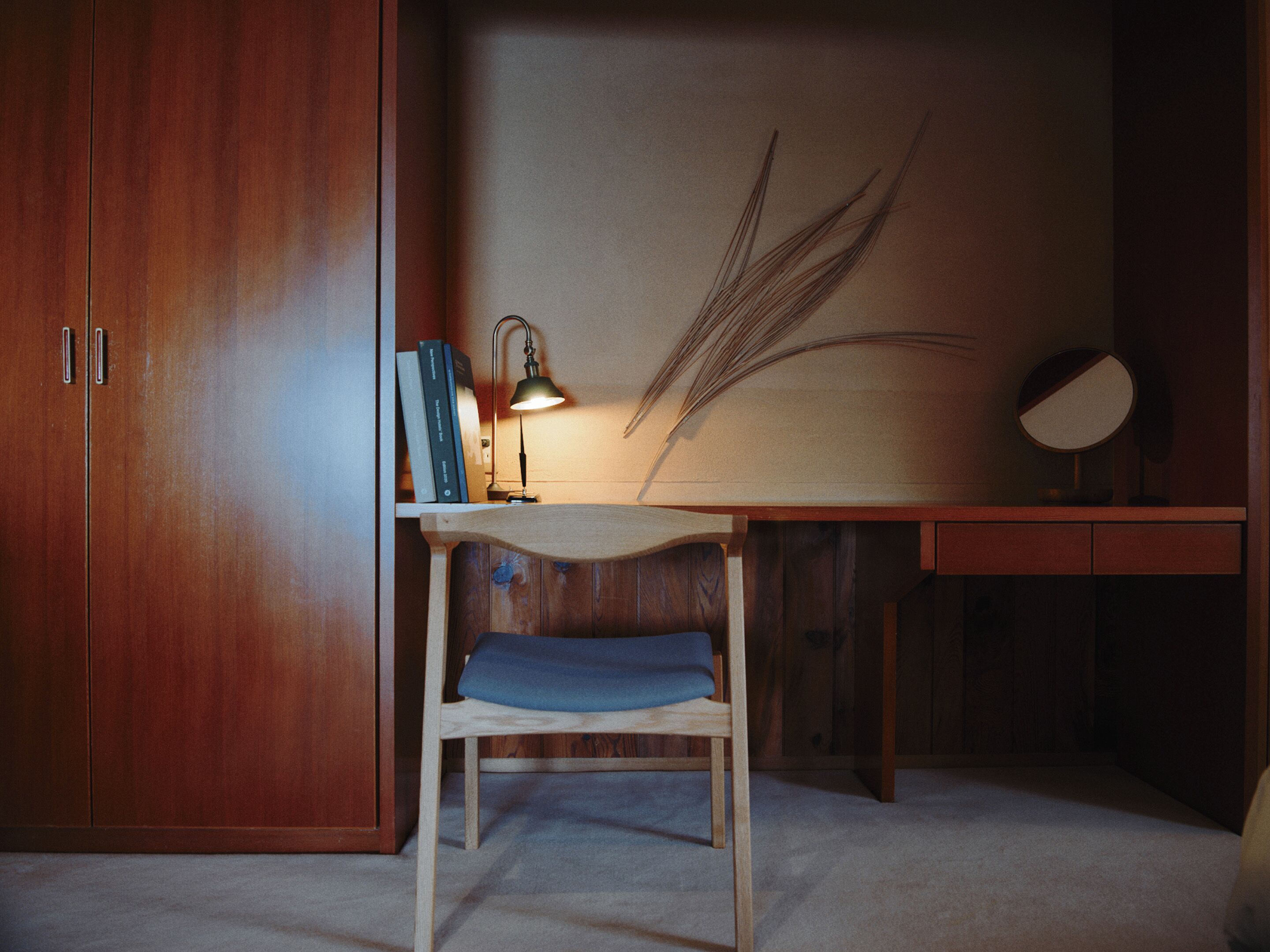 A wooden desk with a lamp, books, and a chair.
