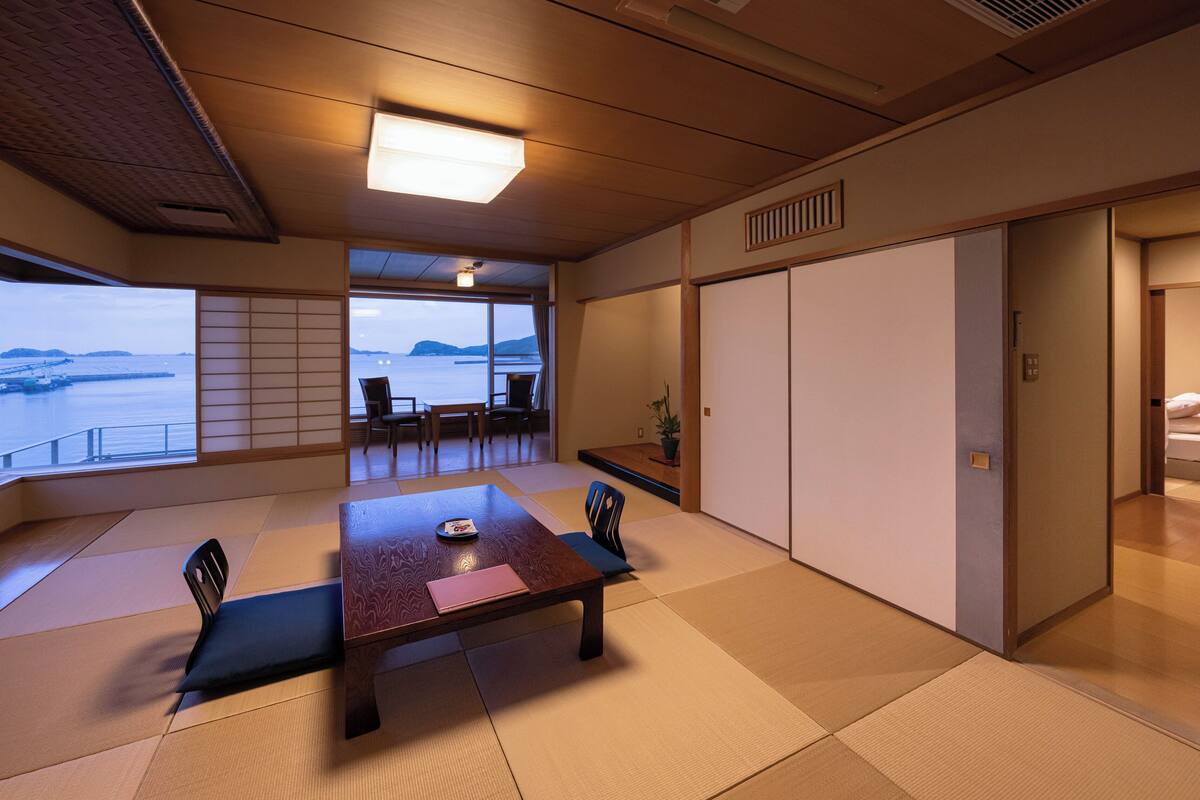 Een traditionele Japanse kamer met tatami vloerbedekking, een lage tafel met kussens en schuifdeuren.