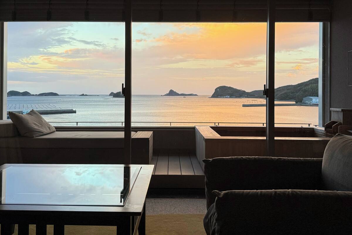 Een moderne woonkamer met een groot raam met uitzicht op de kust.