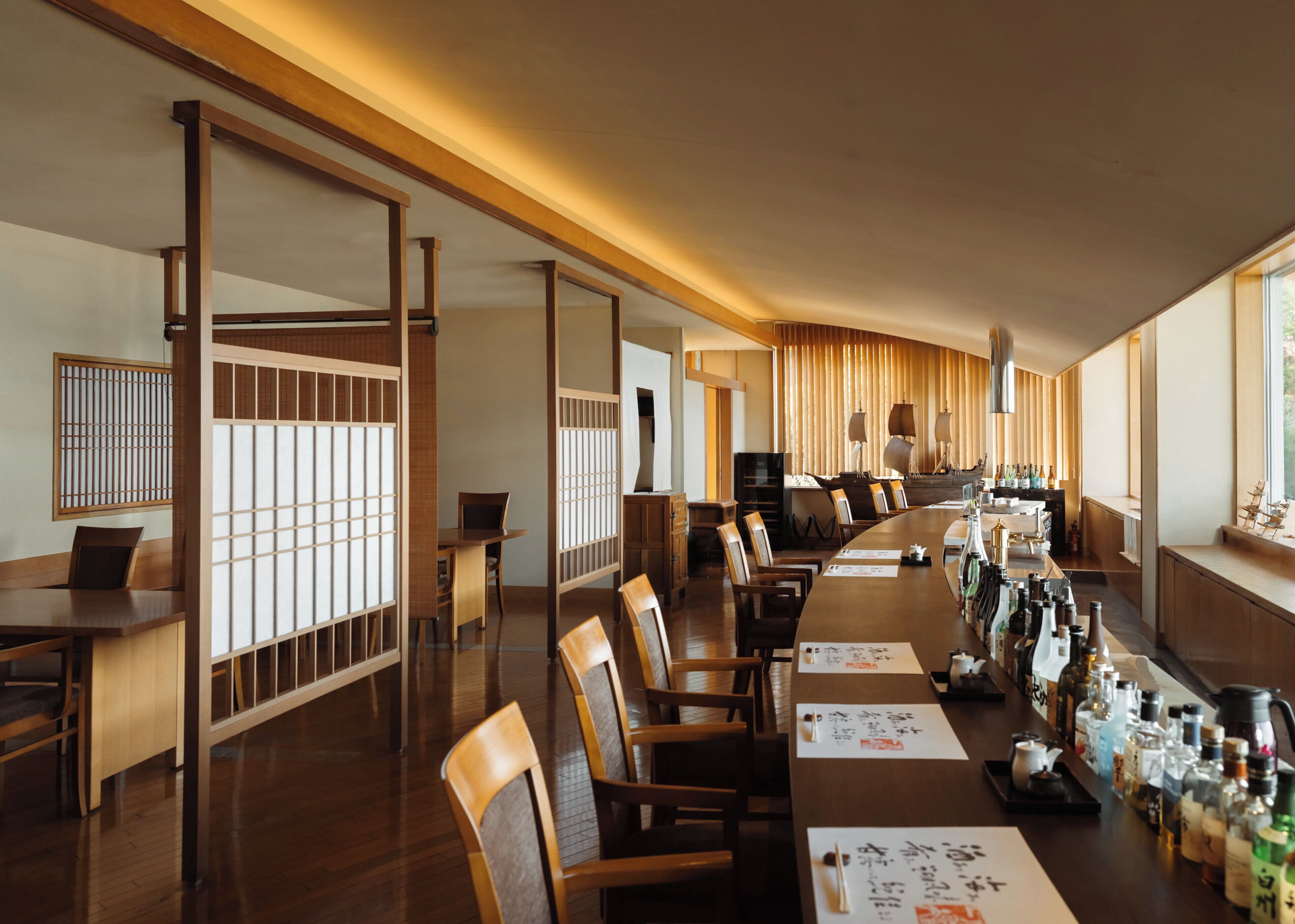 A traditional Japanese restaurant with wooden furniture, tatami mats, and a long counter with bottles.