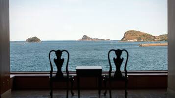 A view from a window with two chairs facing a body of water and distant islands.