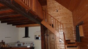 A wooden staircase leading to a lofted area with a kitchen in the background. - Authentic sheepfold renovated  (Sazos)