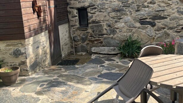 A stone building with a wooden door and a small window. There is a chair and a table outside. - Authentic sheepfold renovated  (Sazos)
