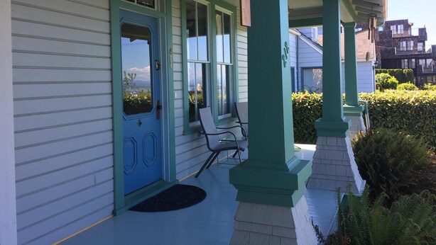 A covered porch with a blue door, two chairs, and a small table. - A View of the Strait of Juan de Fuca (Port Angeles)