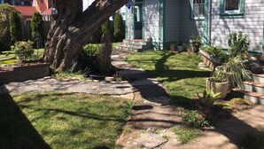 A residential house with a sloped roof, a front yard with a pathway, and a large tree. - A View of the Strait of Juan de Fuca (Port Angeles)