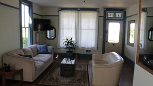 A living room with a beige sofa, a white armchair, a coffee table, and a potted plant. - A View of the Strait of Juan de Fuca (Port Angeles)