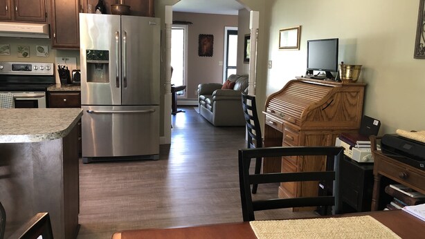 Une cuisine équipée d’un réfrigérateur en acier inoxydable, de meubles de rangement en bois et d’un coin repas avec une table et des chaises en bois.
