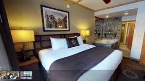 A hotel room with a large bed, a bathroom with a stone wall, and a painting of mountains on the wall. - 1 Bedroom Luxury Villa Ski in/Ski out Park City Westgate Canyons Resort (Park City)
