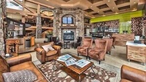 A spacious living area with a stone fireplace, leather sofas, and a high ceiling with exposed beams. - 1 Bedroom Luxury Villa Ski in/Ski out Park City Westgate Canyons Resort (Park City)