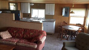 Een ruimtelijk ingerichte leefruimte met kitchenette, eethoek en zithoek.