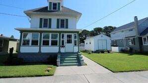 Uma casa de dois andares com varanda frontal e uma pequena escadaria para a entrada.