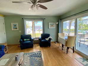 A living room with two armchairs, a small table, a floor lamp, and a view of the outside through large windows.
