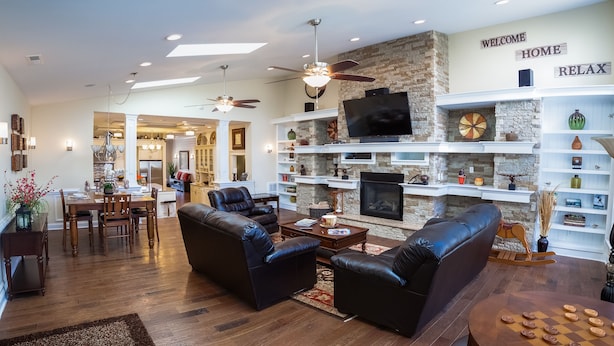 A spacious living room with a fireplace, leather sofas, and a television.