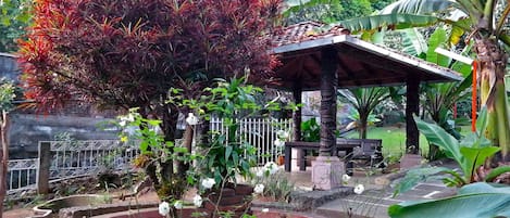 A garden with a gazebo, a red tree, and a white fence.