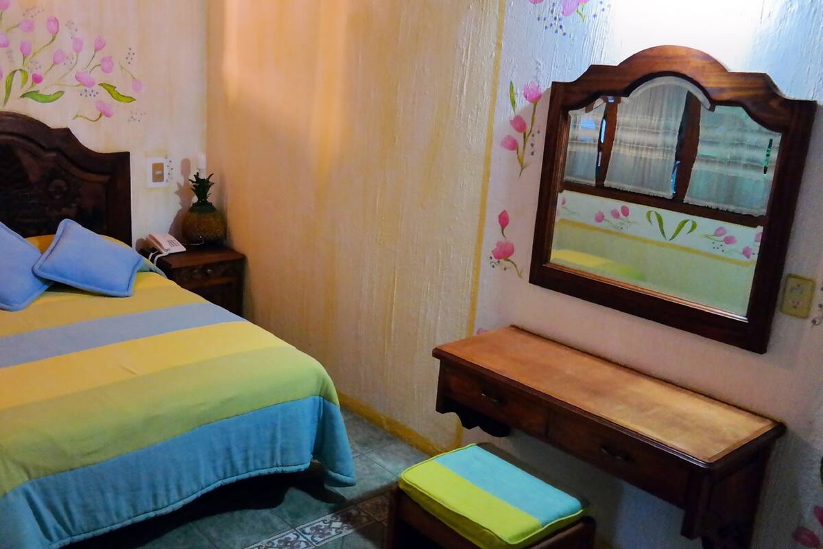 A bedroom with a bed, bedside table, and a mirror.