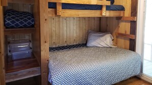 A compact wooden room with bunk beds, a small shelf with storage bins, and a window. - The Roadrunner Tiny Cabin at Palo Duro  (Canyon)
