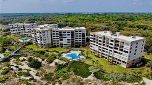 A multi-story hotel complex with a pool area and surrounding greenery.