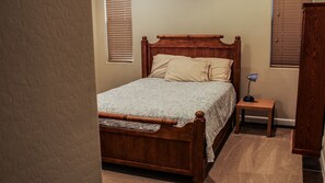 A bedroom with a wooden bed, a nightstand, a lamp, and a wardrobe.