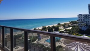 A balcony with a view of a beach, a pool, and a hotel building. - Large Modern 4 Bedroom Beautiful Ocean Views-1003 (Miami Beach)