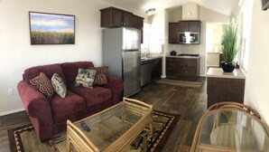 A living room with a red sofa, a glass coffee table, and a kitchen with dark cabinets and stainless steel appliances. - Deluxe "Sunset" Vacation rental in private marina on the California Delta (Stockton)