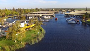 A marina with boats docked, a covered boat ramp, and a grassy area with trees. - Deluxe "Sunset" Vacation rental in private marina on the California Delta (Stockton)