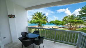 A balcony with a view of the beach, featuring a table and chairs.