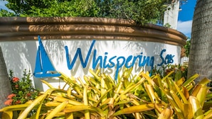 A sign with the name "Whispering Sands" surrounded by tropical plants.