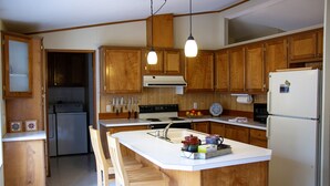 A kitchen with wooden cabinets, a white countertop, a built-in stove, and a refrigerator. - Bellinger Cabin, wooded getaway near Sisters, Central Oregon (Sisters)