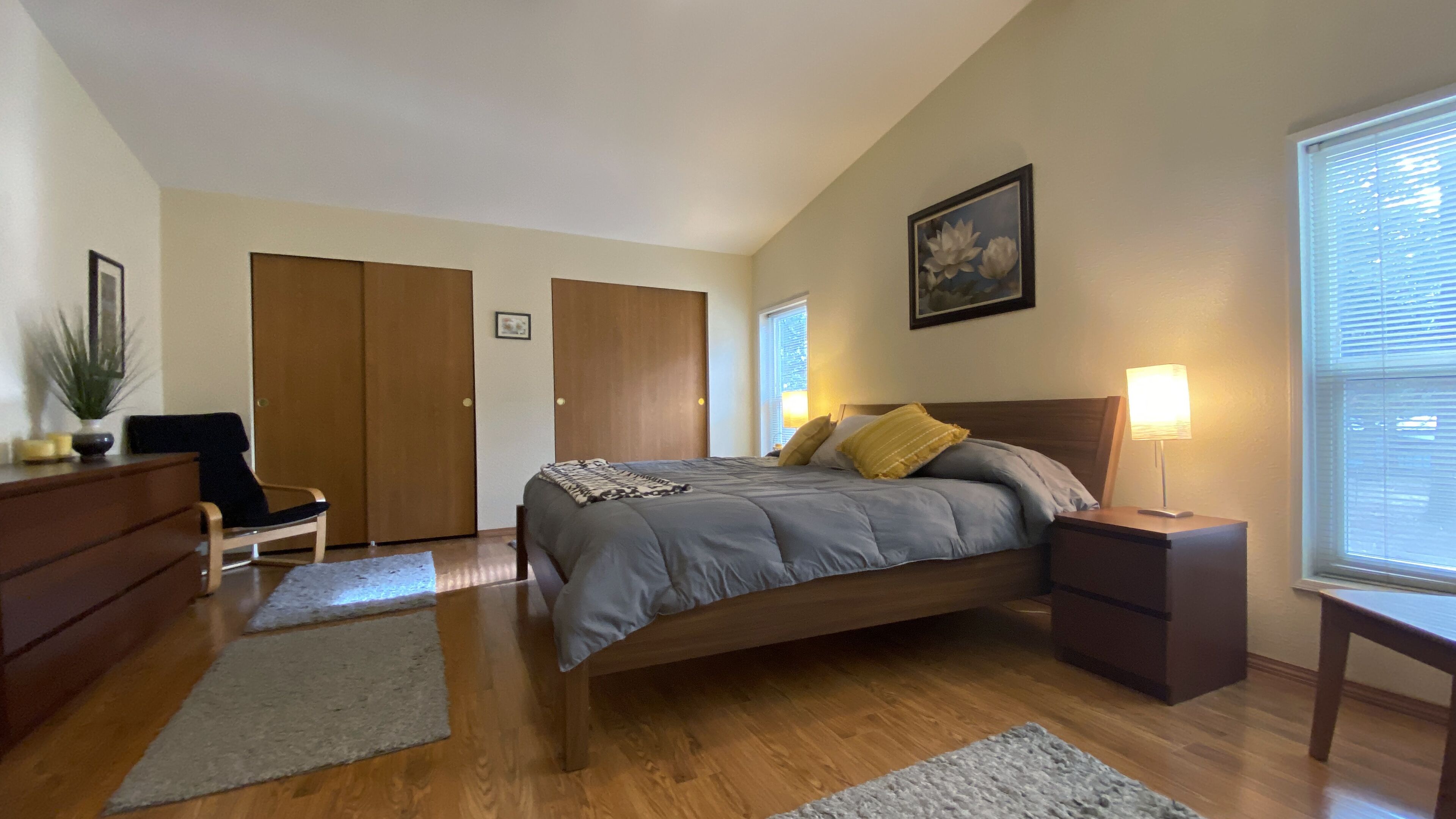 A bedroom with a bed, nightstands, a dresser, a chair, and a window with blinds.