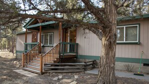 A cabin with a wooden staircase, a porch, and a large tree in front. - Bellinger Cabin, wooded getaway near Sisters, Central Oregon (Sisters)
