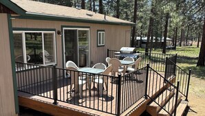 A wooden deck with outdoor furniture, a grill, and a covered patio area. - Bellinger Cabin, wooded getaway near Sisters, Central Oregon (Sisters)