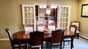 A dining room with a wooden table and chairs, a chandelier, and a cabinet with glass doors. - Happy Valley retreat - whole house, large living room, EV charger (Port Matilda)