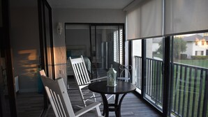 A balcony with a table and chairs, a view of the outside, and a door leading to another room. - Beautiful island escape in beach community (Fort Pierce)