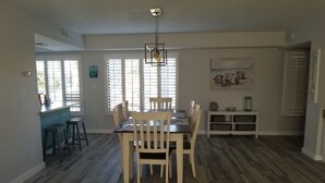 A dining area with a wooden table and chairs, a kitchen area with a blue countertop, and a painting on the wall. - Beautiful island escape in beach community (Fort Pierce)