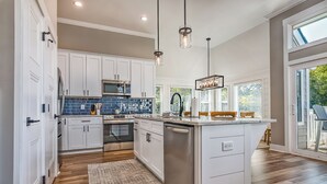 Una cocina moderna con armarios blancos, una isla central e iluminación colgante.