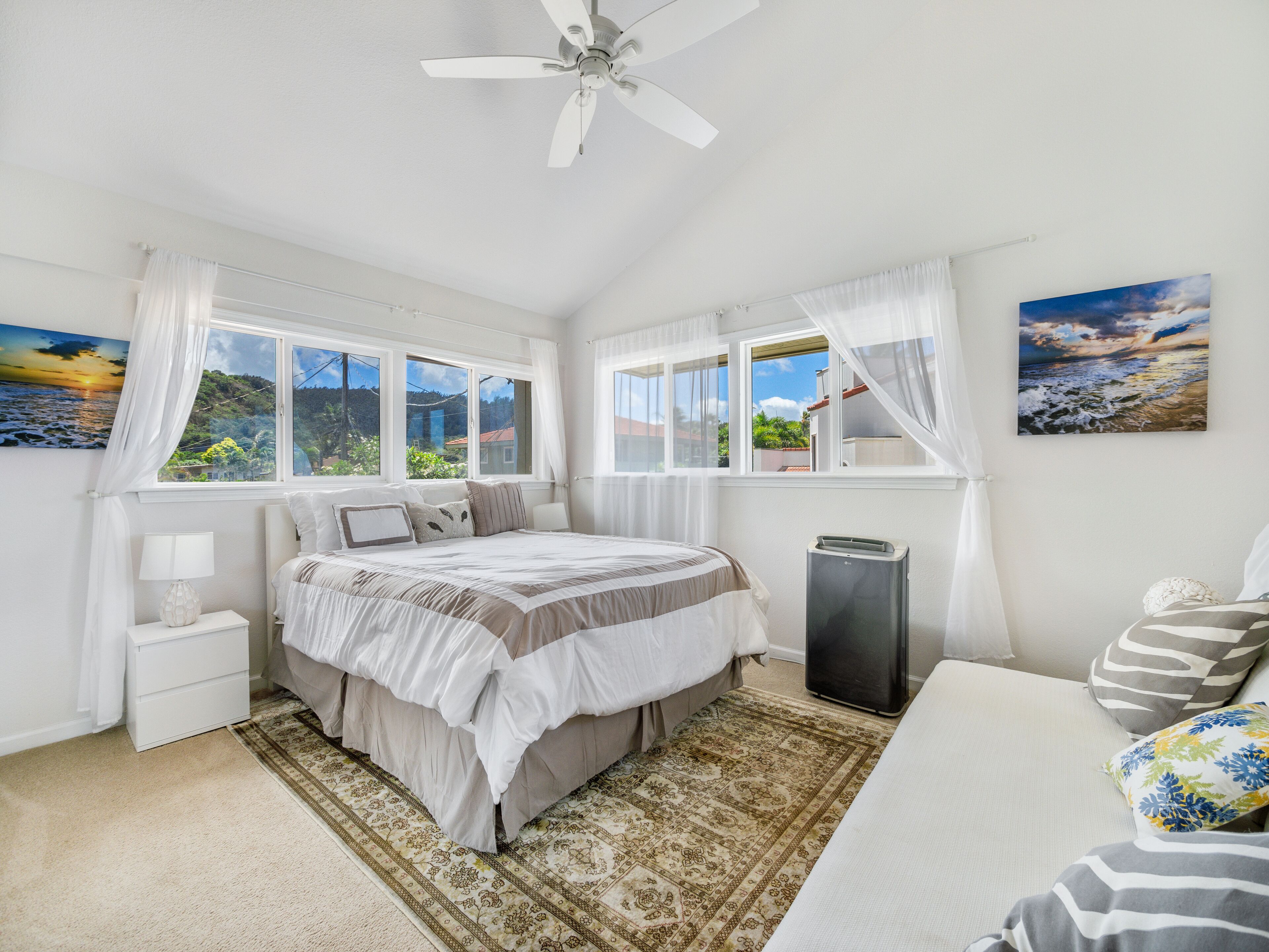 Un dormitorio con cama, mesita de noche, calefactor y ventana con vista al mar.