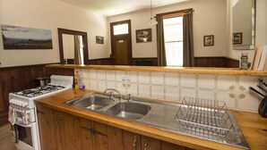 A kitchen with a stove, sink, and wooden cabinets.