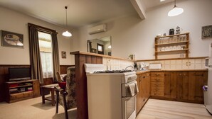 A compact kitchen with a gas stove, wooden cabinets, and a tiled backsplash.