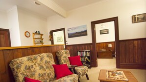 A living room with floral-patterned sofas, a wooden coffee table, and a bookshelf filled with books.