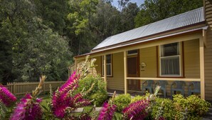 A yellow building with a porch and a wooden fence.