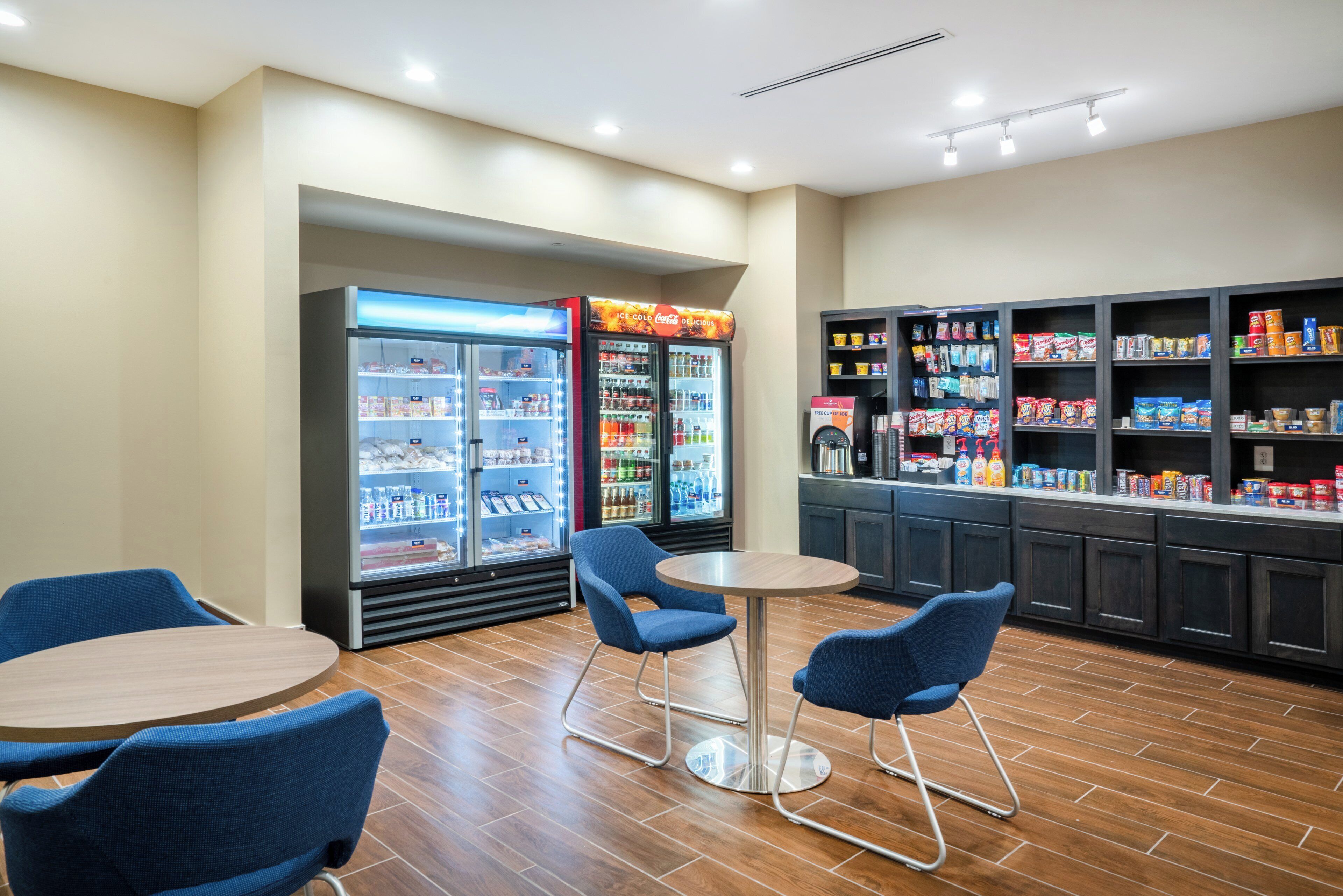 A food service area with seating, a beverage cooler, and a snack display.