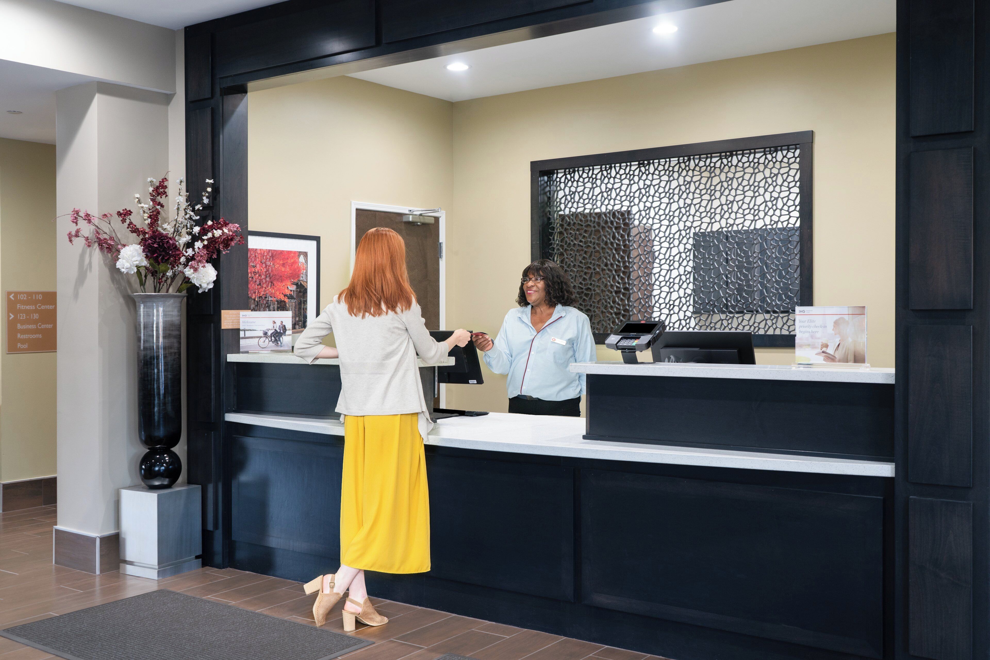 A reception area with a reception desk, a framed picture on the wall, and a sign indicating the location of the fitness center.