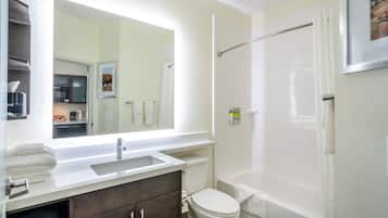 Un baño con lavamanos, espejo, inodoro y bañera.
