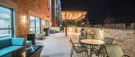 An outdoor patio area with brick walls, a seating area with a fire feature, and a grill station.