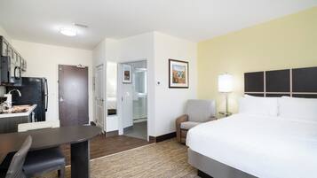 Una habitación de hotel con una cama, un escritorio, una silla, una lámpara y un cuadro en la pared.