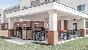 A covered outdoor area with barbecue grills, a trash bin, and a red object on the ground. - Candlewood Suites Nashville - Franklin by IHG (Franklin)