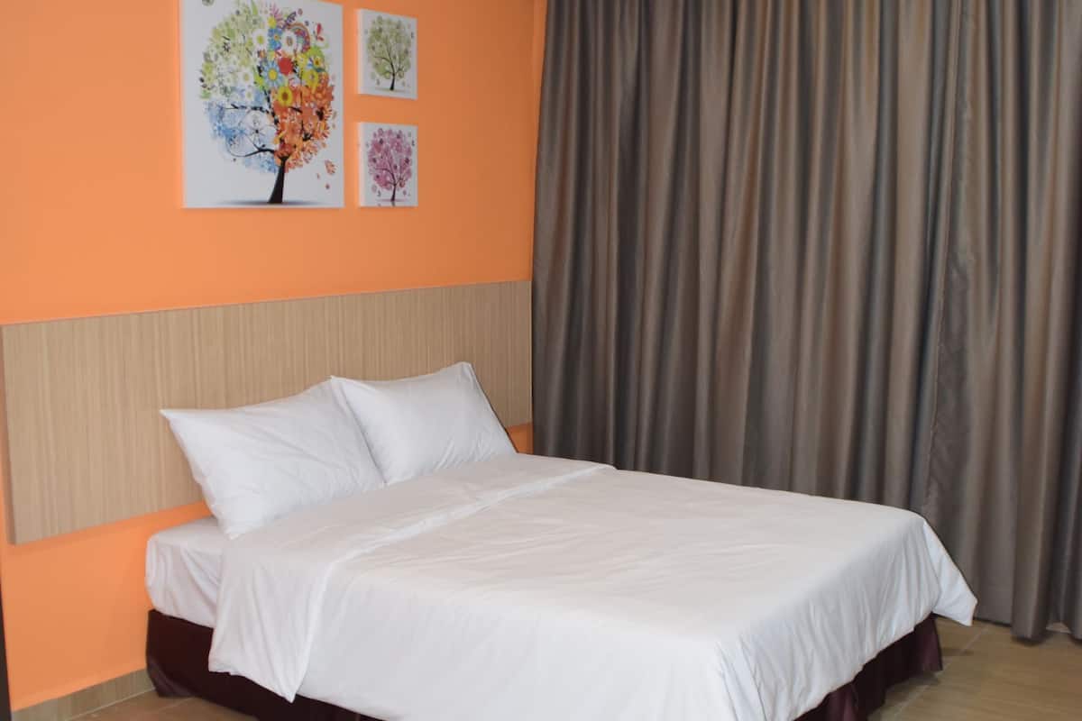 Une chambre d’hôtel avec un lit, des murs orange et une grande fenêtre avec des rideaux.