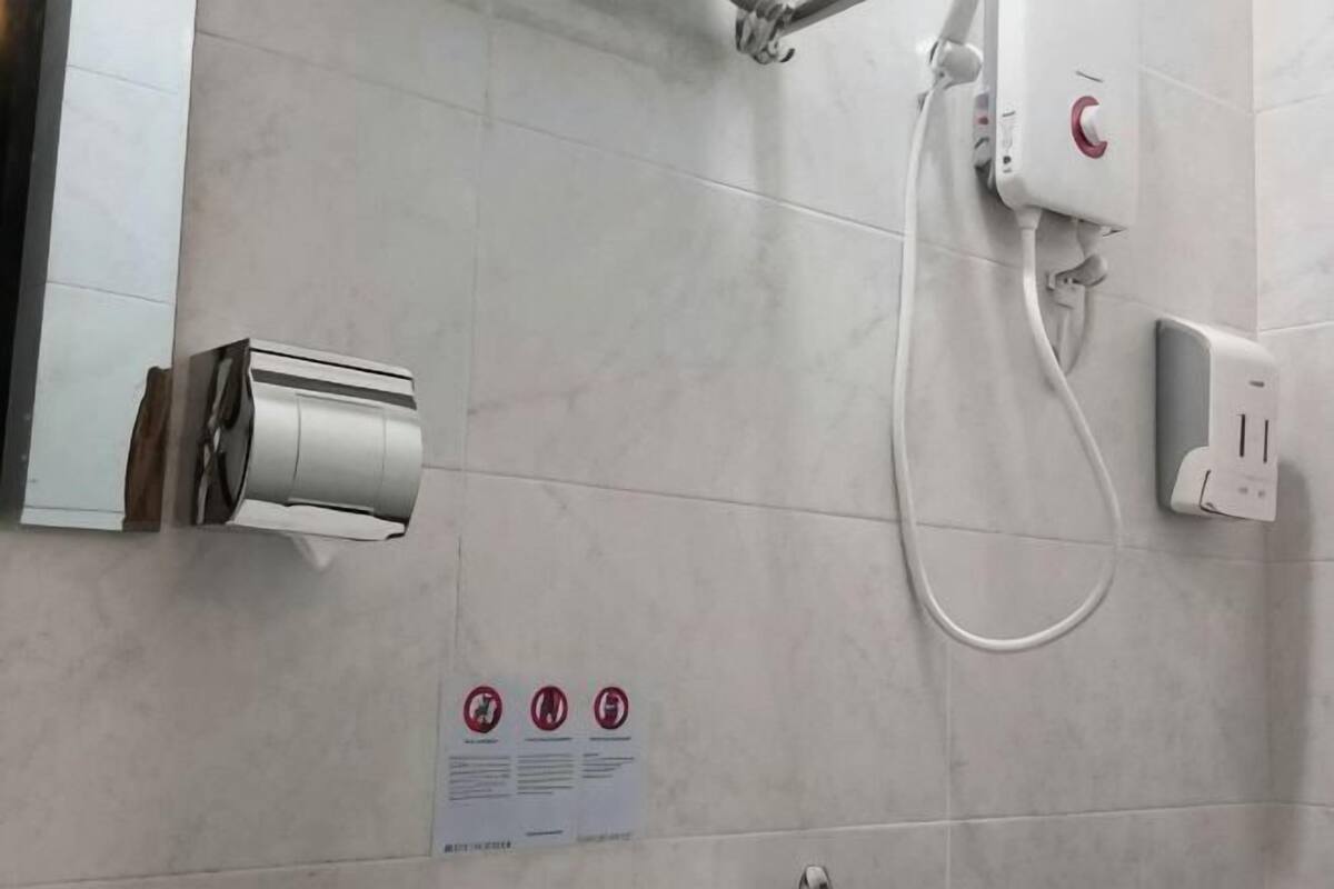 Une salle de bain équipée d’une douche, d’un sèche-mains et d’un panneau indiquant les consignes.