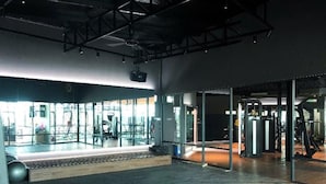 Un gimnasio espacioso con paredes de espejo, equipo de ejercicio y suelo de madera.