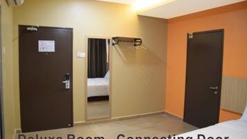 A deluxe room with a connecting door, a bed, a mirror, and a coat rack.